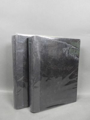 two black books sitting on top of each other on a white surface