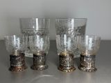 four glasses and a cup on a table with a silver base