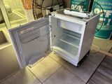 an open refrigerator sitting on a tile floor in a room