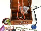 une boîte en bois remplie d'un assortiment de colliers et de bracelets