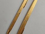 two gold colored pens sitting next to each other on top of a table