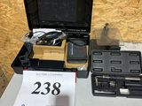 une mallette noire portant un numéro, à côté d'une autre mallette noire portant un numéro