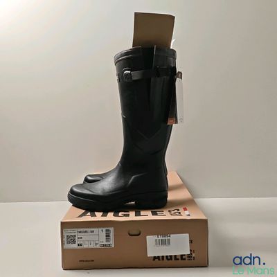 des bottes en caoutchouc noires posées sur une boîte en carton, sur une surface blanche