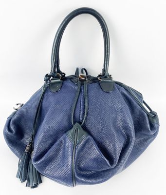 un sac à main bleu avec un pompon suspendu à la poignée
