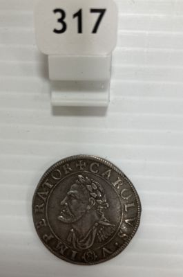une pièce d'argent posée sur une table blanche, à côté d'une étiquette blanche