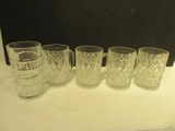 four glasses and a pitcher are lined up on a counter