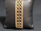 a close up of a pillow with a gold bracelet on it