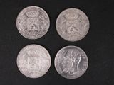 four different british coins on a black surface with a black background