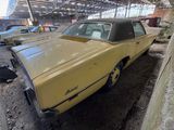 an old yellow car is parked in a garage with other cars in the background