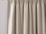 a close up of a beige curtain with a gold rod
