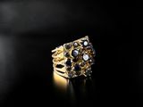 a close up of a gold ring with black stones on a black surface