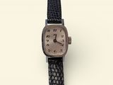 une image représentant une montre-bracelet avec un cadran marron et un bracelet en cuir noir