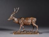 une statue en bronze représentant un cerf, posée sur un socle en bois