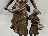 a bronze statue of a woman holding a child on top of a wooden base