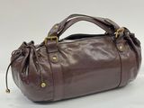 the brown leather bag is sitting on a white surface