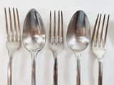 five forks and a spoon on a white surface
