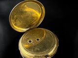 an image of a close up of a gold pocket watch on a black surface