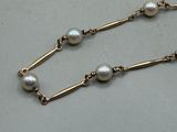 necklace with pearls and gold chain on a white surface