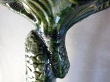 a close up of a green vase with a bird on it