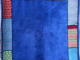 une image représentant un tapis en patchwork coloré sur fond bleu