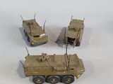 three toy army vehicles sitting on top of a white surface