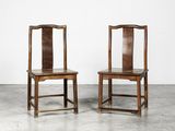 two wooden chairs sitting next to each other on a cement floor