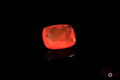 a close up of a glowing red diamond on a black surface
