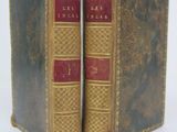 an old pair of books sitting next to each other on a white surface