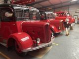 row of red fire trucks parked in a garage next to each other