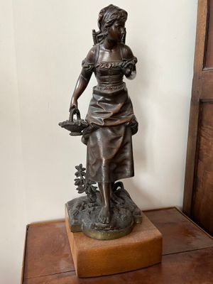 une statue représentant une femme tenant un panier de fleurs posé sur une table