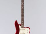 a red electric guitar hanging from a white wall