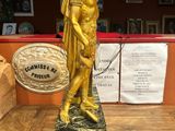 gold statue of a man holding a shield on a wooden table