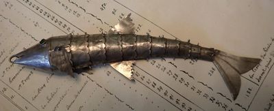 un poisson en métal posé sur une feuille de papier