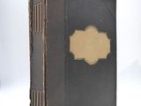 a black book with a gold label sitting on a white surface