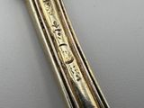 a silver spoon with a gold handle on a white surface