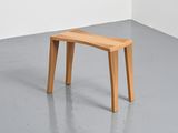 a small wooden bench in a room with a white wall