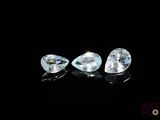 a pair of blue topazte pear shaped diamonds on a black surface