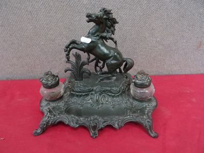 statue en bronze représentant un cheval avec un cavalier sur le dos, posée sur un socle rouge
