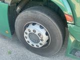 a green truck with a flat tire parked on the side of the road