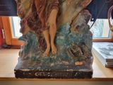 a statue of a woman sitting on top of a rock