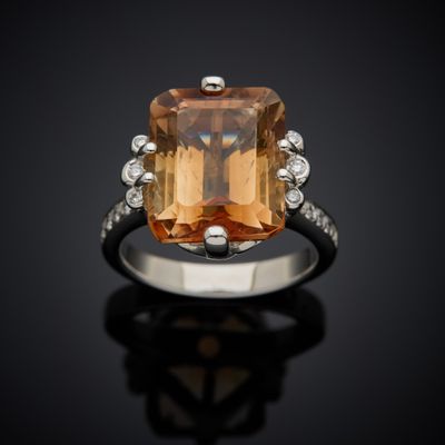 an orange topazte and diamond ring on a black surface