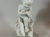 a small statue of a boy sitting on a stool