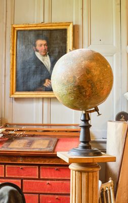 un grand globe terrestre posé sur un bureau, devant un tableau