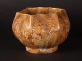 a brown bowl sitting on top of a table next to a black background