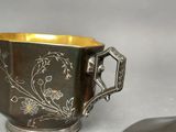 a silver cup with a flower design on it and a spoon