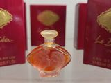 bottles of perfume sitting on a table in front of red boxes