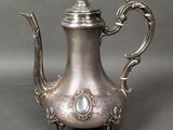 an antique silver tea pot with a bird on top of it