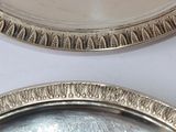 two silver plates on a white table with a white background