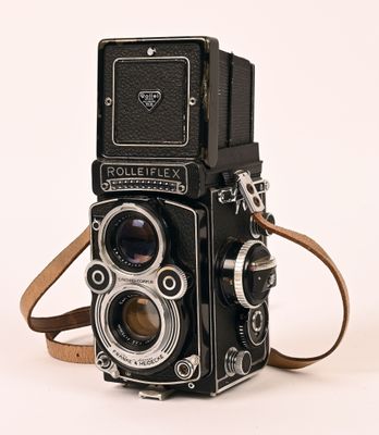 a black camera with a brown strap on a white background