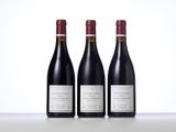 three bottles of red wine sitting on top of a table